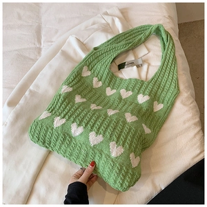 Détail du cabas en tricot vert avec motifs de cœurs et étiquette métallique sur coton doux