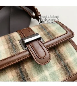 Detail of plaid wool texture and brown leather edges with precision manual stitching