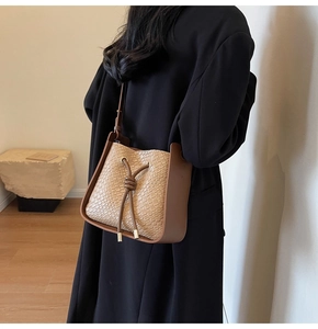 Detail of woven bucket bag with drawstring closure and golden metal accents