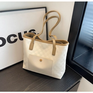 Detail of cream woven tote bag featuring a front pocket with button and brown trim