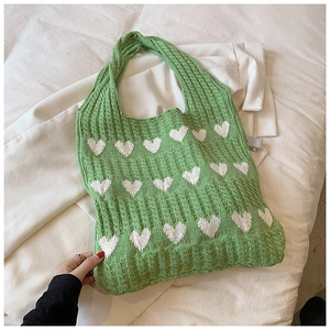 Gros plan du sac cabas en tricot vert avec motifs de cœurs blancs et texture douce