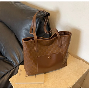 Macro detail of brown checkered tote bag featuring a front pocket with snap closure