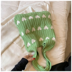Gros plan détaillé du sac cabas tricoté vert avec motifs cœurs blancs et texture souple