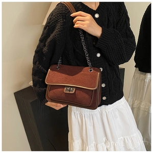 Detail of quilted dark burgundy crossbody bag with vintage metal turn-lock and chain strap