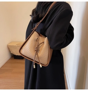 Detail of a brown woven bucket bag featuring a drawstring closure and a shoulder strap