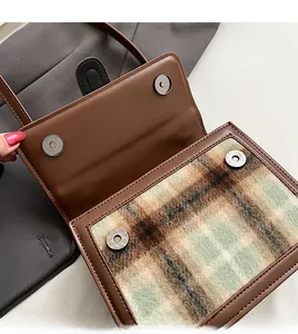 Detail of brown faux leather handbag showing double magnetic snap closures and plaid plush texture