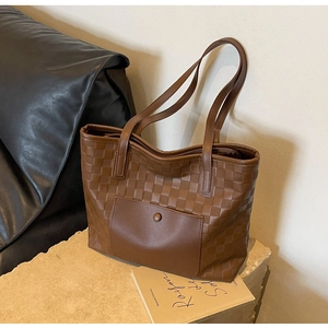 Detail of checkered woven texture and leather front pocket on brown tote bag