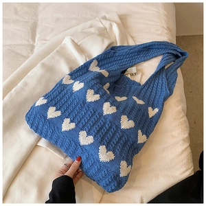 Détail du sac cabas en tricot bleu avec motifs de cœurs blancs et texture douce