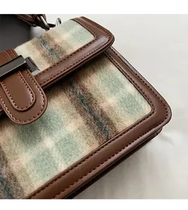 Close-up of brown faux leather trim and soft textured plaid fabric on the small square bag