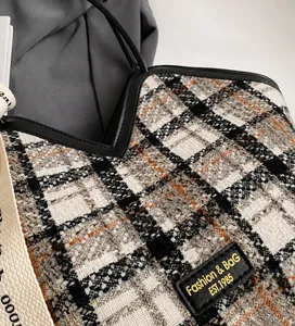 Close-up of retro plaid tote bag showing tweed texture and black leather handle details
