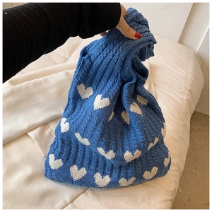 Gros plan détaillé du sac en maille bleue avec motifs cœurs blancs et maille torsadée