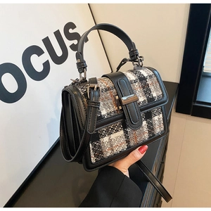 Detailed view of black and white tweed texture and gunmetal buckle on the handbag