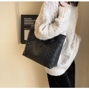 Close-up of black checkered tote bag with front pocket and metal snap button detail
