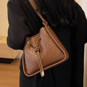 Brown woven leather bucket bag with drawstring closure and wide shoulder strap style
