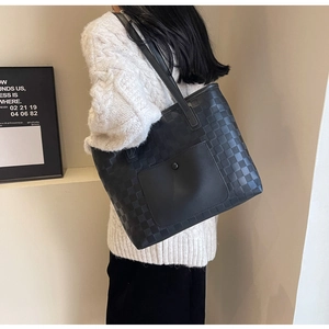 Detail of checkered tote bag with front pocket shown on shoulder in minimalist setting