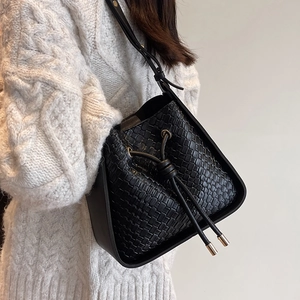 Chic black woven leather bucket bag with drawstring and golden accents on a model
