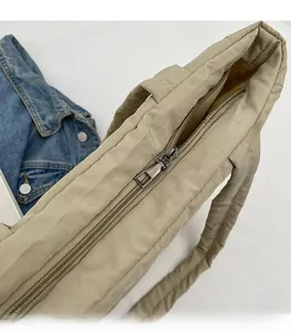 Close-up of smooth metal zipper and quilted fabric texture on beige tote handbag