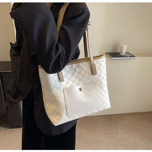 Macro detail of cream checkered woven tote bag with front pocket and leather texture