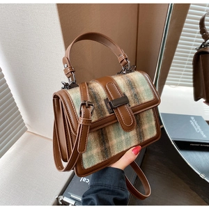 Detail of vintage plaid woolen handbag with leather trim and metallic buckle closure