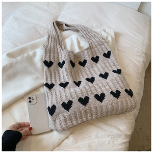 Détail du sac cabas en maille avoine avec motifs de cœurs noirs en jacquard et texture côtelée