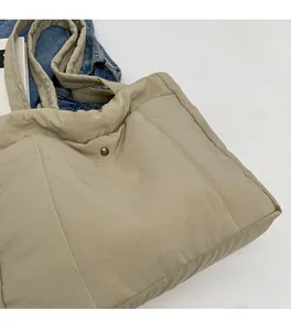 Close-up of beige quilted tote bag showing soft V-shaped stitching and padded texture