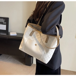 Detail view of woven checkered tote bag with cream leather handles and front pocket