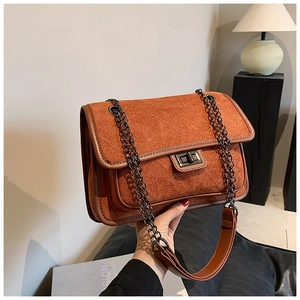 Detail of brown quilted suede shoulder bag with metal chain strap and twist lock