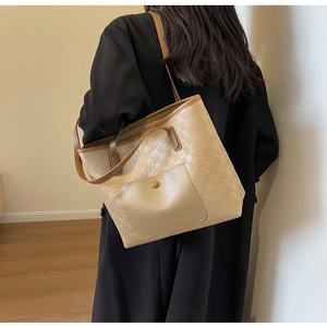 Detailed back view of a beige checkered woven tote bag worn by a model in a minimalist room