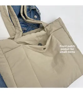 Detail view of khaki quilted tote bag featuring a front patch pocket for small items