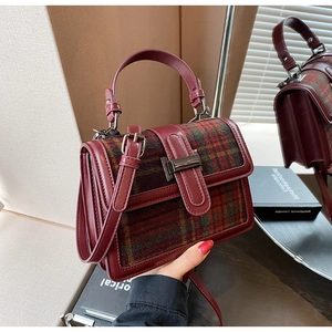 Detail of burgundy leather and plaid wool texture on stylish women square handbag