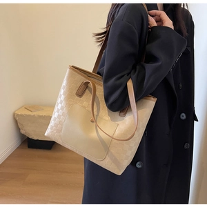 Detail of beige tote bag featuring square embossed texture and contrast brown pocket