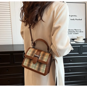 Detailed side view of a plaid handbag with leather trim worn by a model in a retro setting