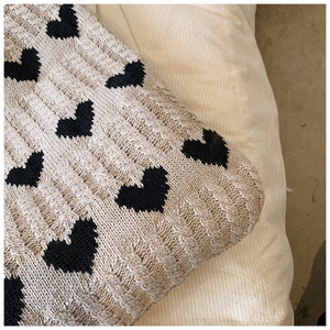 Vue détaillée du sac cabas en tricot beige avec motifs de cœurs noirs et torsades