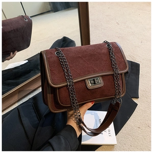 Detailed shot of burgundy suede quilted bag with metallic clasp and chain strap