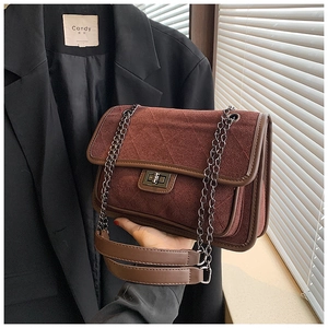 Macro shot of dark burgundy quilted chain bag showing rotating lock and leather edge