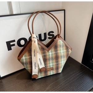 Macro detail of plaid tote bag showing V-shaped opening and decorative logo ribbon