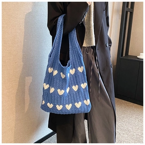 Sac fourre-tout en tricot bleu à motif cœur porté à l'épaule dans un intérieur