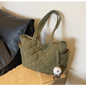 Close-up of quilted nylon tote bag in army green with a plush white charm detail