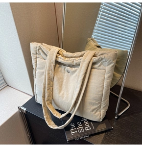 Detail of beige quilted nylon tote bag showing double shoulder straps and magnetic closure