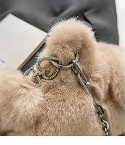 Gros plan détaillé du sac en fausse fourrure beige avec fermoir coeur argenté et chaîne