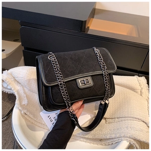 Detail of black quilted chain bag featuring matte suede flap and silver metal turn-lock