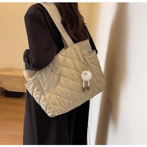 Quilted nylon tote bag with plush charm, showing shoulder strap detail and soft texture