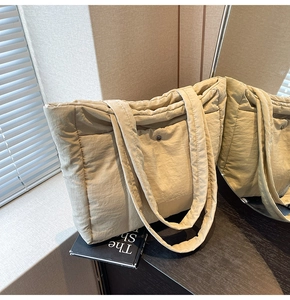 Detail of quilted nylon tote bag with magnetic closure on a wooden surface with mirror