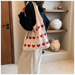 Détails du tissage du sac cabas en tricot blanc cassé avec motifs de cœurs rouges à l'épaule