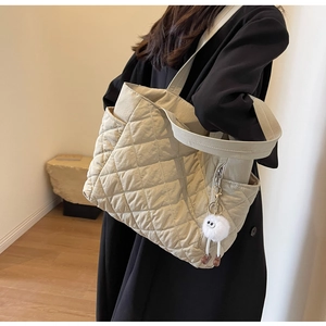 Quilted nylon tote bag detail featuring a functional side zipper and plush monster charm