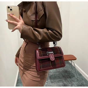 Detail view of burgundy leather and green plaid shoulder bag with vintage metal clasp