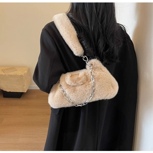 Détail du sac à bandoulière beige en fausse fourrure avec chaîne sur un blazer noir