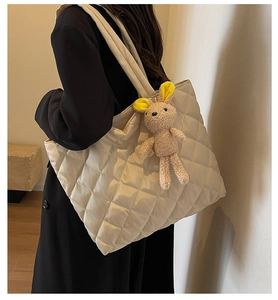 Detail of beige quilted nylon tote bag with cute plush bunny charm and thick straps