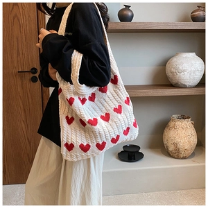 Détail du sac cabas en tricot à motif cœur montrant la texture épaisse sur modèle