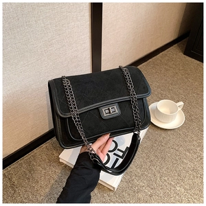Detail of black quilted chain bag with matte texture and square metal twist lock clasp